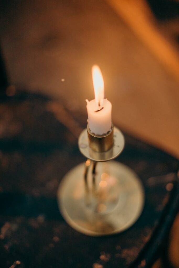 A warmly lit candle in a brass holder creates a cozy and intimate atmosphere with a soft glow.